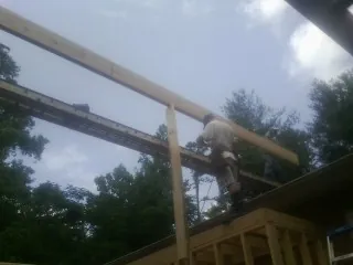 Carpenter setting a ridge beam over a new addition frame — Ice Dam Removal by Roofing Brothers in Goldsboro